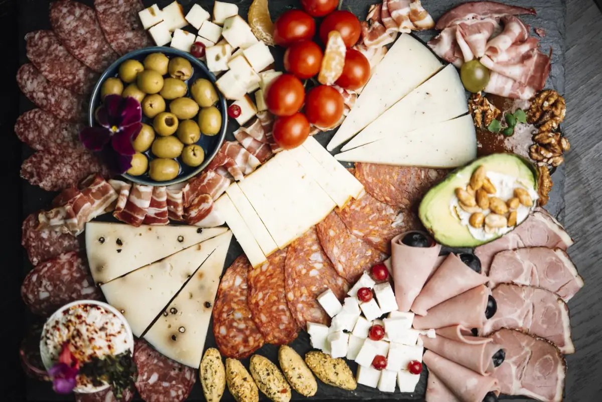 Planche garnie de charcuteries, fromages, olives et fruits à partager